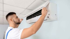 Teknisi sedang memeriksa evaporator AC saat cuaca panas di dalam ruangan
