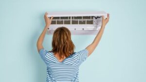 orang sedang memeriksa evaporator AC yang menyebabkan konsumsi listrik meningkat