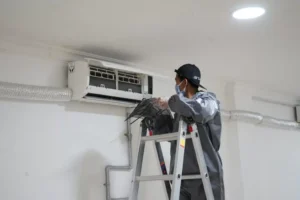 Teknisi sedang memeriksa evaporator AC berisik di dalam rumah Kenapa Evaporator AC Berisik Saat Dinyalakan? Ini Penjelasa