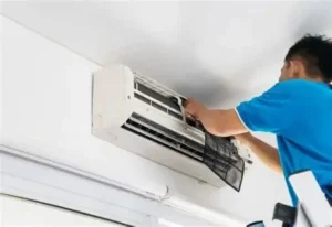 Teknisi sedang memeriksa unit AC inverter di ruangan rumah