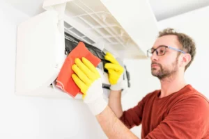 teknisi membersihkan evaporator AC berwarna kuning